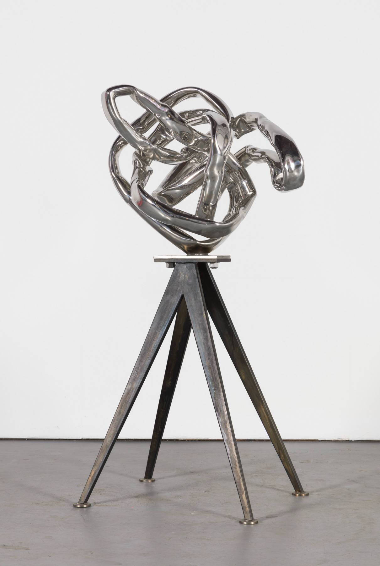 Twisted metal sculpture on thing metal legs as a base.
